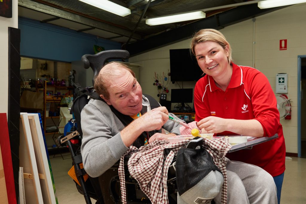 A Woodside volunteer helping Rocky Bay client with an art project.